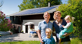 Eine Familie steht vor ihrem Haus mit Solardach, symbolisiert Deutschland machts effizient