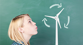 Young woman blowing on an wind turbine