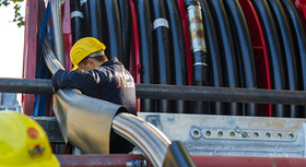 Bauarbeiter rollt Supraleiterkabel von der Spule ab