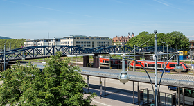 Bahnhof mit Brücke und Zug im Hintergrund