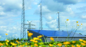 Windräder, Strommasten und Photovoltaikanlage auf einer blühenden Wiese