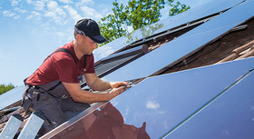 Monteur bringt Fotovoltaikanlage auf einem Dach an.