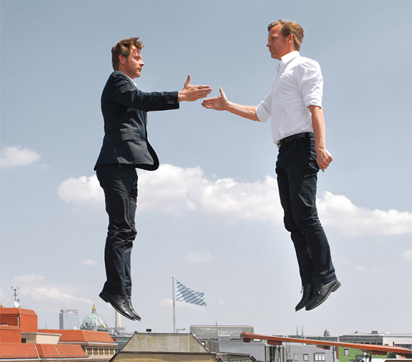 Zwei fliegende Geschäftsmänner reichen sich die Hände.