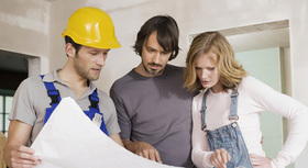 Bauingenieur und junge Hauseigentümer besprechen Bauplan auf der Baustelle.
