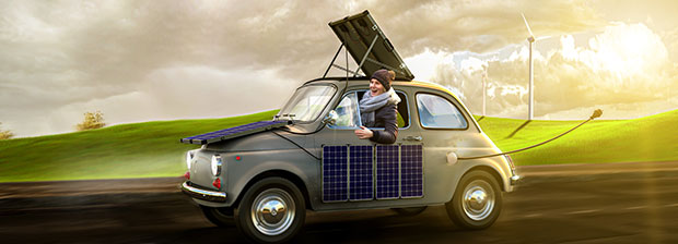 Frau fährt mit ihrem Elektroauto übers Land und lädt dieses mittels Solarenergie