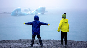 Zwei Kinder stehen am Ufer eines Eismeeres
