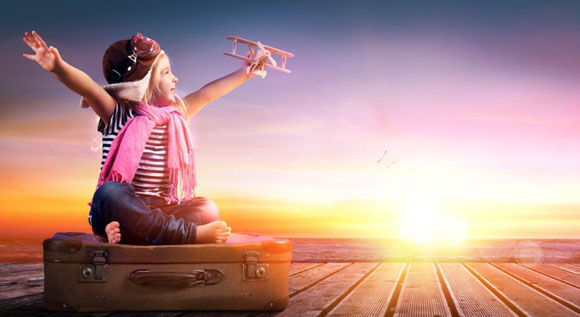 Mädchen sitz mit Spielzeugflugzeug auf gepacktem Koffer